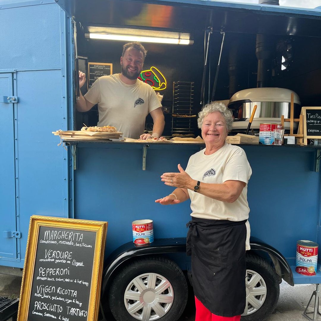 Ties serveert een gast vanuit de blauwe pizzakar